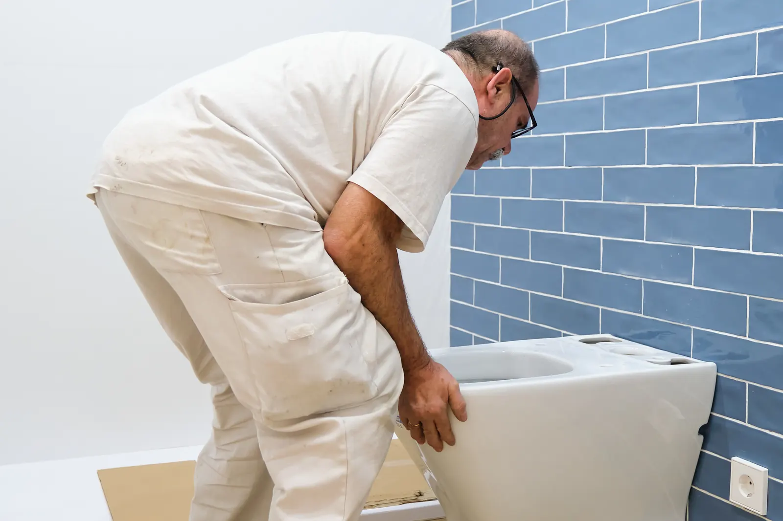 Een loodgieter monteert een toilet in een badkamer