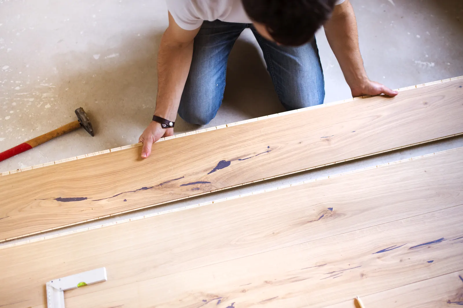 Een klusser legt een houten vloerdeel op zijn plek